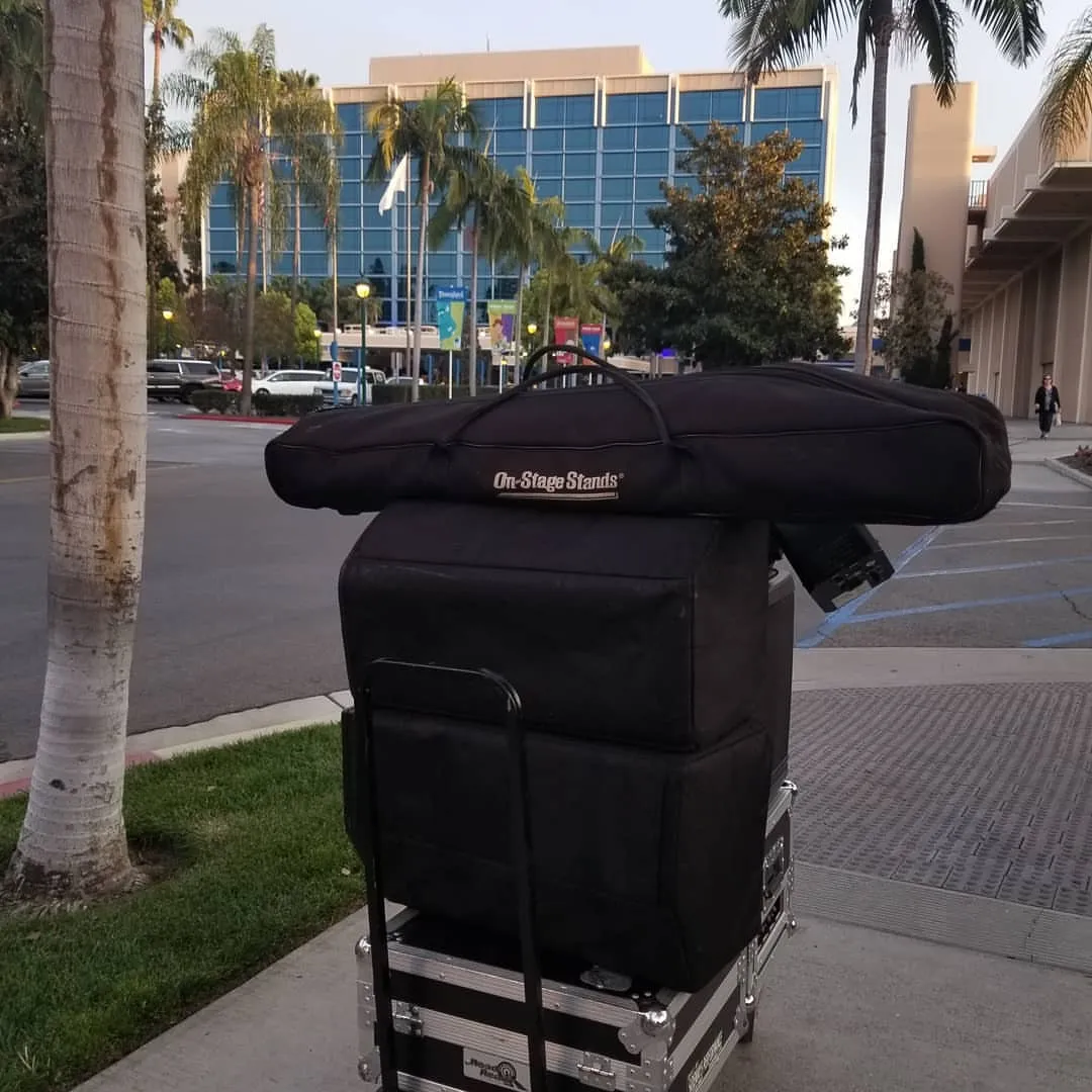 Packed DJ gear cases loaded on a cart outside a venue