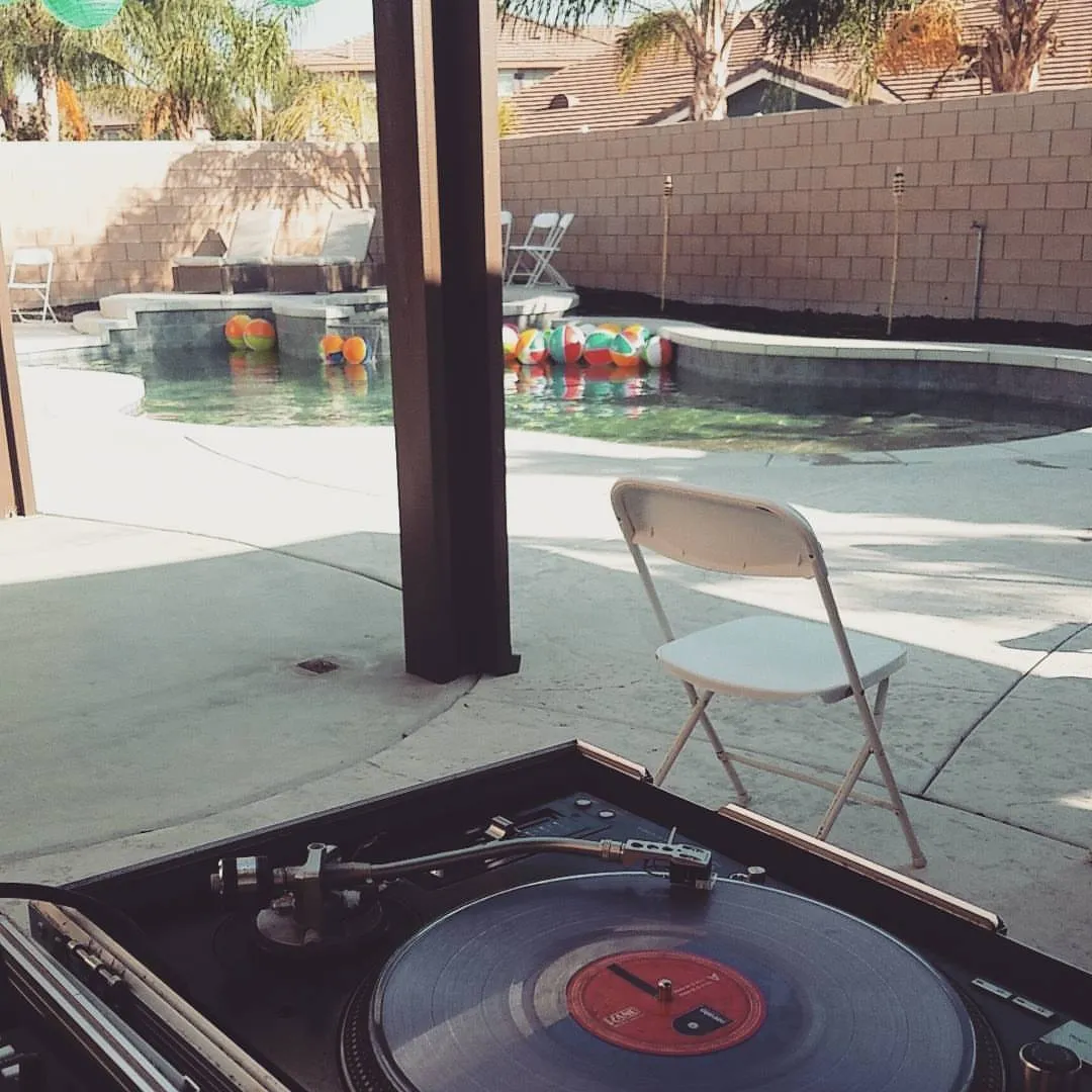 Turntable set up beside a backyard pool in daylight