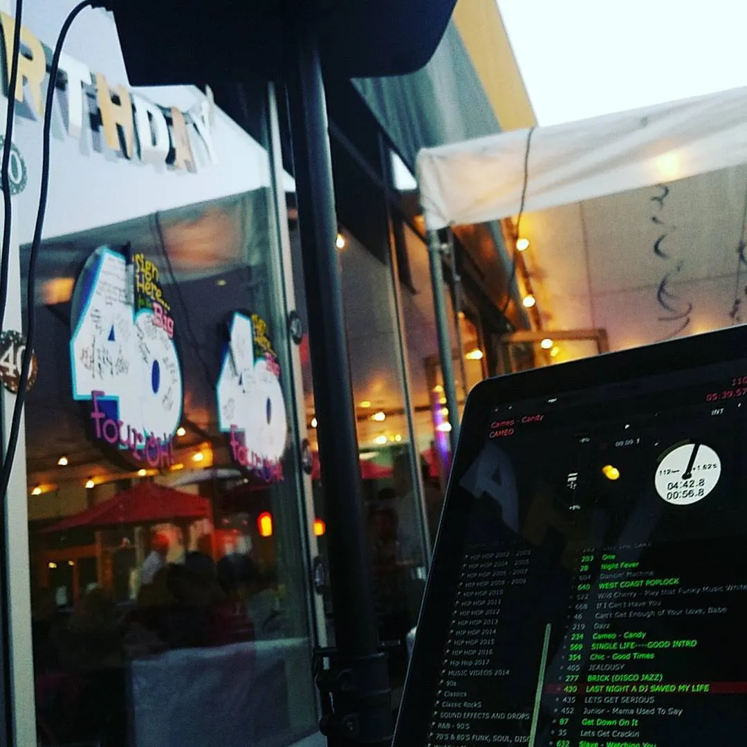 Outdoor birthday party at night behind the DJ laptop